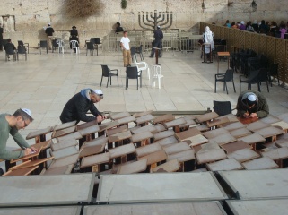 Jewish men writing their prayers down at the Western Wall during Chanukah